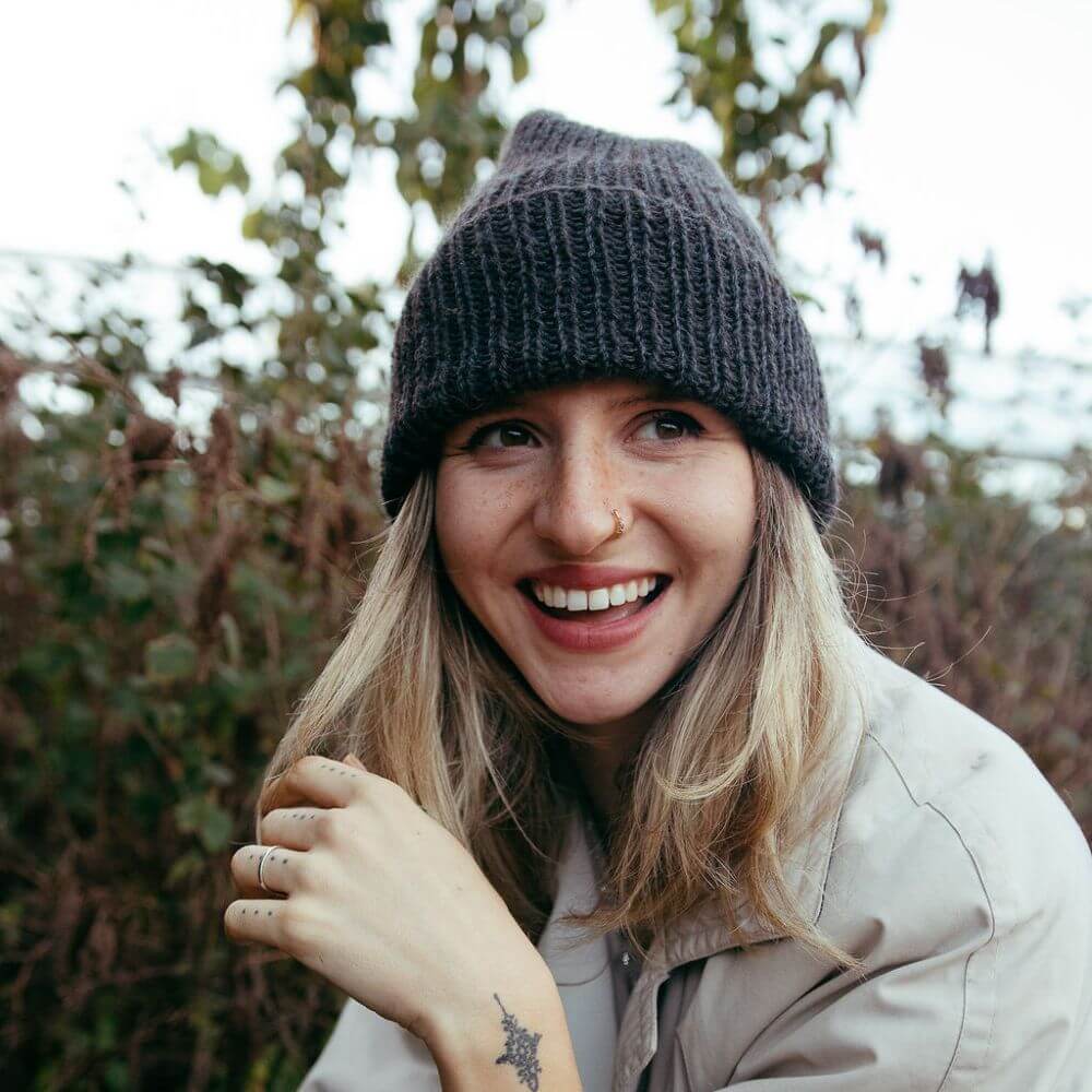 Model wearing the alpaca wool chunky hat knitting kit uses alpaca yarn from British and Irish farms. Shown here in Speckledy Grey.