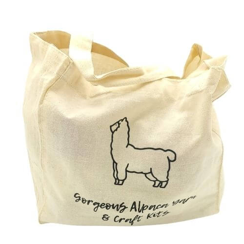 Cream tote bag with alpaca design and text on a white background