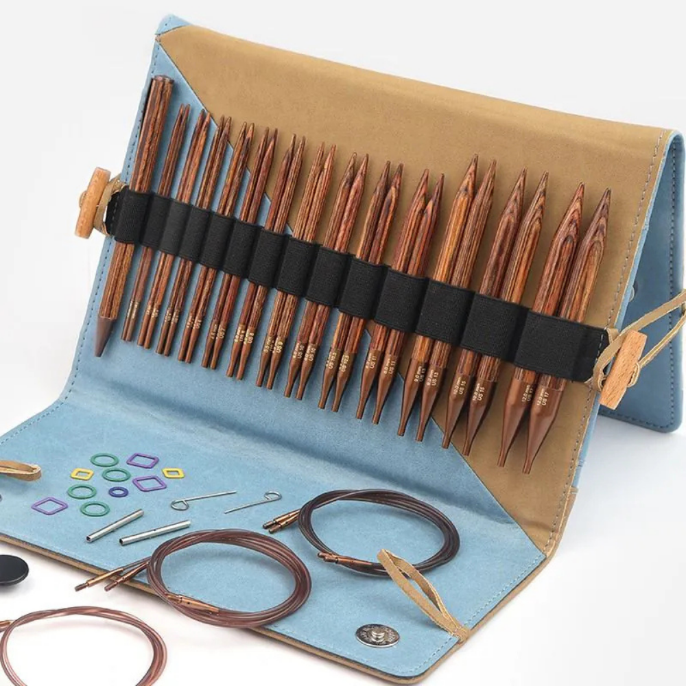 Set of wooden knitting needles in a blue and brown case on a white background